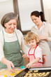Little girl with grandmother cutting out cookies