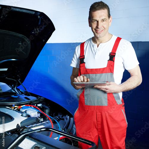 Foto: Motor mechanic in a garage working with touchpad Motor mechanic in a garage working with touchpad