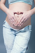 Fingers forming heart shape over navel on belly Fingers forming heart shape over navel on belly