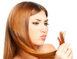 Foto: Beautiful woman holding split ends of her hair and frown Beautiful woman holding split ends of her hair and frown