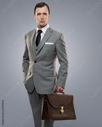 Photo: Businessman with a briefcase isolated on grey. Businessman with a briefcase isolated on grey.