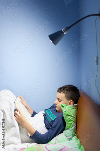 Photo: Kid reading a book at bedtime Kid reading a book at bedtime