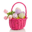 cheerful easter eggs and tulips in a pink wicker basket isolated