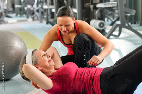 Photo: Senior woman exercise abdominal in fitness center Senior woman exercise abdominal in fitness center