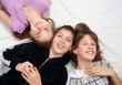 Smiling teenage girls and  teenage boy resting on bed