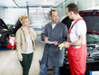 Female customer takes advise by motor mechanics in a garage