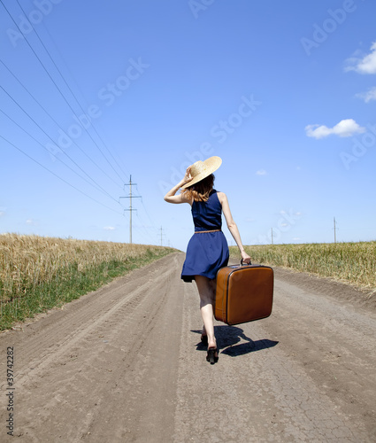 Photo: Lonely girl with suitcase at country road. Lonely girl with suitcase at country road.