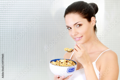 Photo: Jeune femme mangeant des céréales au petit déjeuner Jeune femme mangeant des céréales au petit déjeuner