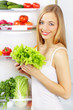 girl with a green salad. Background of the refrigerator