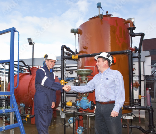 Photo: Two petrochemical contractors closing a deal in front of an oil Two petrochemical contractors closing a deal in front of an oil
