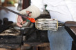 Glass blower shaping molten glass