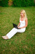 Young beautiful woman working with laptop in the green grass