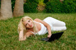Young beautiful woman working with laptop in the green grass