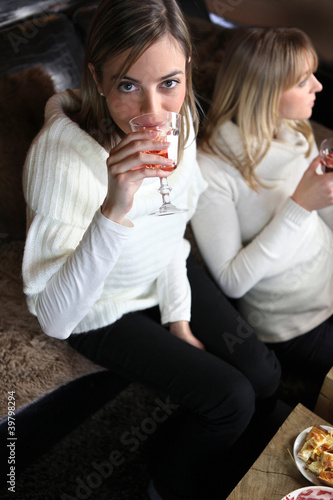 Photo: Two women enjoying glass of wine on sofa Two women enjoying glass of wine on sofa