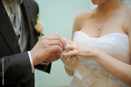 Photo: Groom is putting a ring on bride's finger Groom is putting a ring on bride's finger