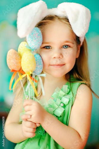 Photo: sweet little girl dressed in Easter bunny ears holding colorfull sweet little girl dressed in Easter bunny ears holding colorfull