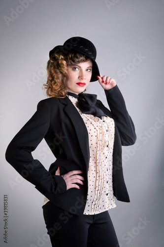 Photo: The girl in a black suit and in a hat poses in studio The girl in a black suit and in a hat poses in studio