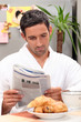 man having breakfast with newspaper