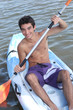 Young man paddling in an open kayak