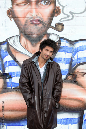 Photo: young man posing in front of graffiti wall young man posing in front of graffiti wall
