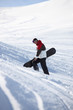 Snowboarder walking up a mountainside