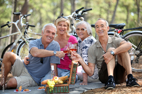 Photo: Two older couples enjoying a picnic in the woods Two older couples enjoying a picnic in the woods