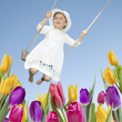 Happy childhood - swinging girl in spring garden