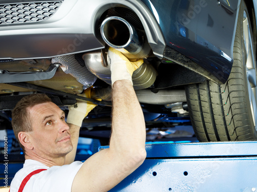 Photo: Motor mechanic fixing the exhaust system of a car Motor mechanic fixing the exhaust system of a car
