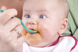 baby girl eating her first mashed carrot