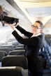 businesswoman putting her luggage into overhead locker