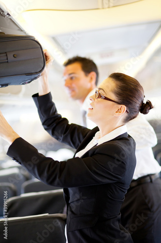 Photo: friendly flight attendant helping passenger with luggage friendly flight attendant helping passenger with luggage