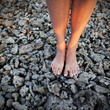 Close-up: girl's legs on death corals barefoot
