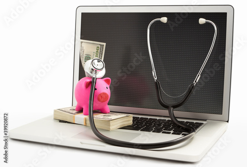 Photo: Piggy bank with stethoscope on laptop Piggy bank with stethoscope on laptop