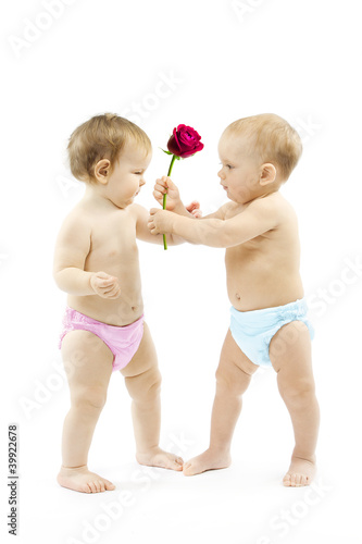 Photo: Baby boy present rose flower to a baby girl. Children wear color Baby boy present rose flower to a baby girl. Children wear color