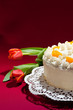 Sahnetorte mit Tulpen auf rotem Hintergrund