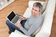 Senior man sitting in sofa and using laptop