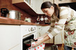 Housewife taking frying pan from oven