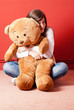 Photo: Young woman embracing teddy bear sitting on floor Young woman embracing teddy bear sitting on floor