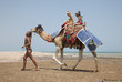 Young beautiful woman rolls the children on a camel