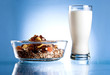 Dish of muesli and glass of fresh milk on a blue background