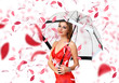 Pretty woman under umbrella with petals around her