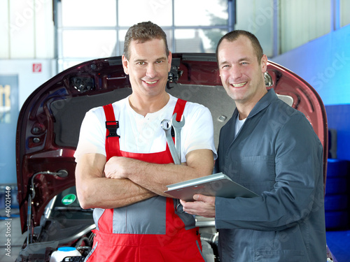 Foto: Two motor mechanics in a garage checking the engine bay Two motor mechanics in a garage checking the engine bay