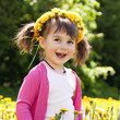 A smiling girl sitting on the dandelion field with the dandelion