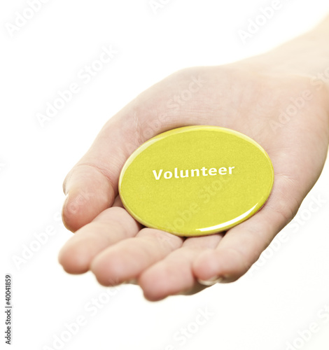 Photo: Hand holding volunteer button Hand holding volunteer button