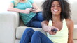 Black woman watching TV while a friend is on a couch