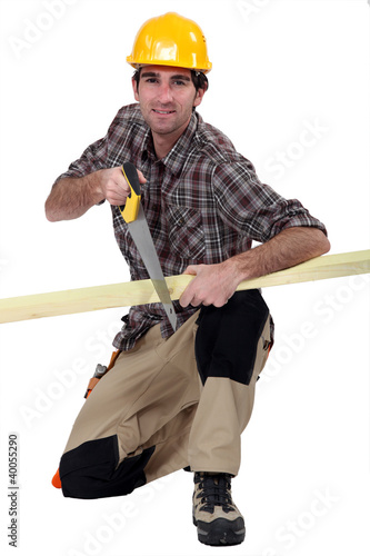 Photo: A carpenter sawing a plank of wood. A carpenter sawing a plank of wood.