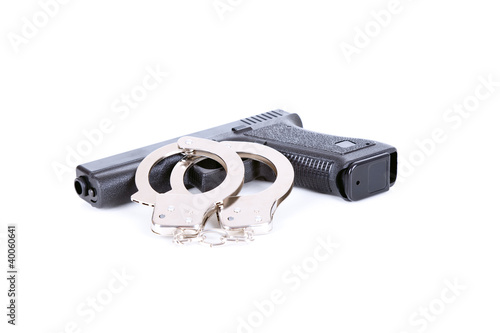 Photo: gun and steel handcuffs lying on the white background gun and steel handcuffs lying on the white background