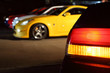 Number of multi-colored cars in parking. Focus on red rear lamp.
