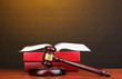 Judge's gavel and books on wooden table on brown background Judge's gavel and books on wooden table on brown background