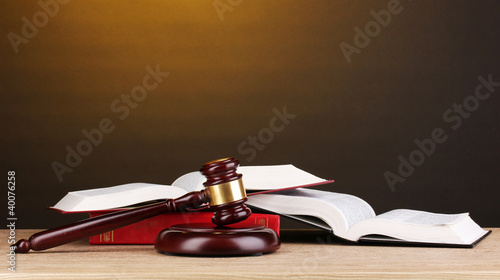 Foto: Judge's gavel and books on wooden table on brown background Judge's gavel and books on wooden table on brown background